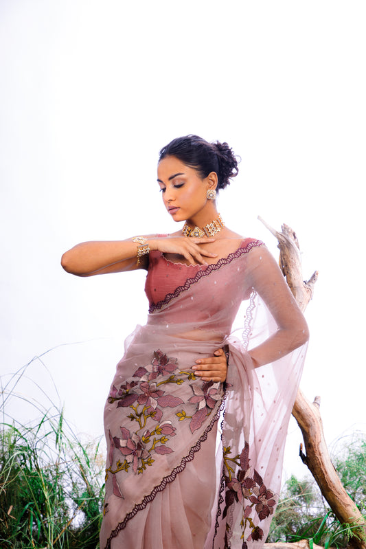 The saree features an enchanting display of 3D embroidered floral motifs that cascade like a blooming vine across the fabric.