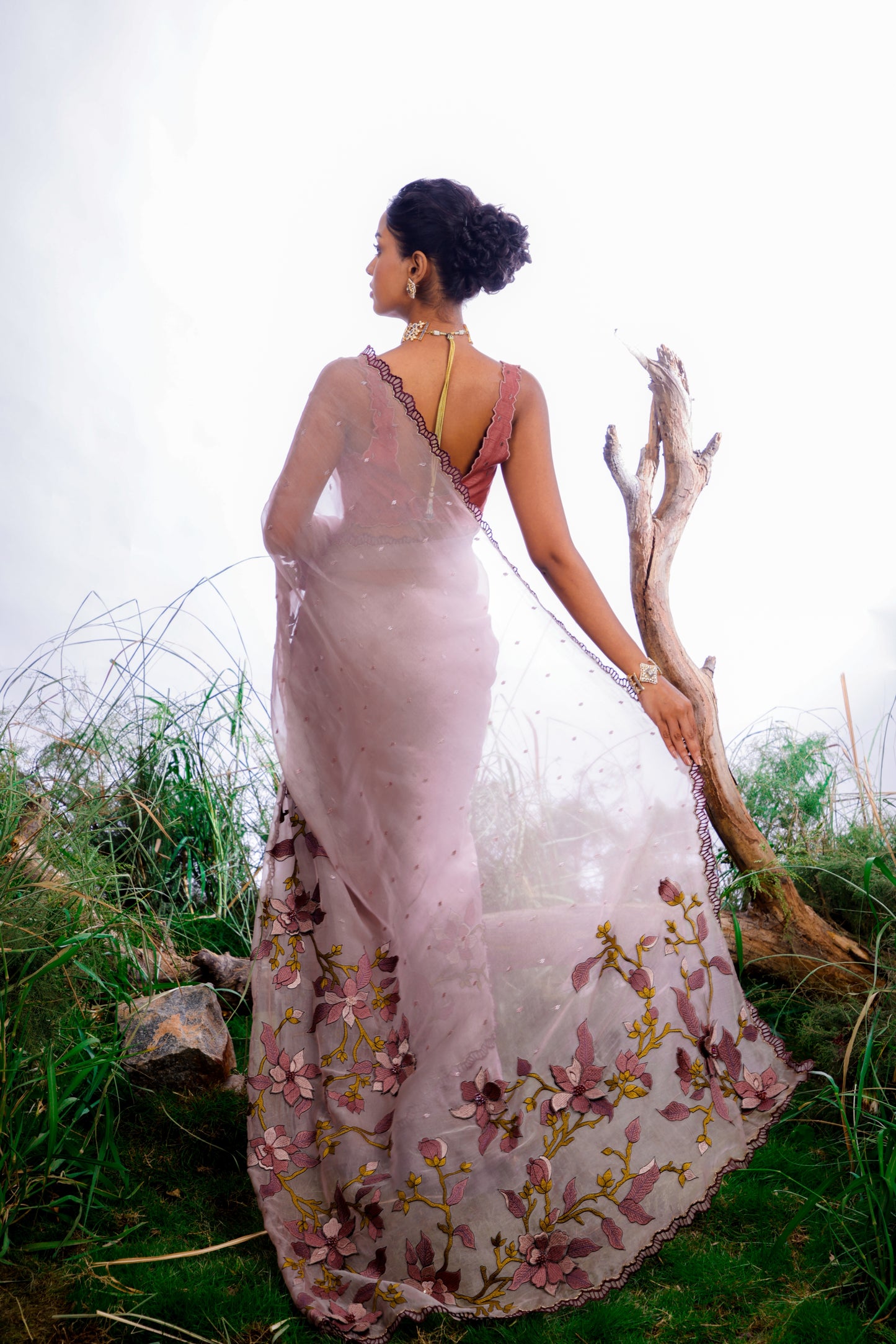 The saree features an enchanting display of 3D embroidered floral motifs that cascade like a blooming vine across the fabric.