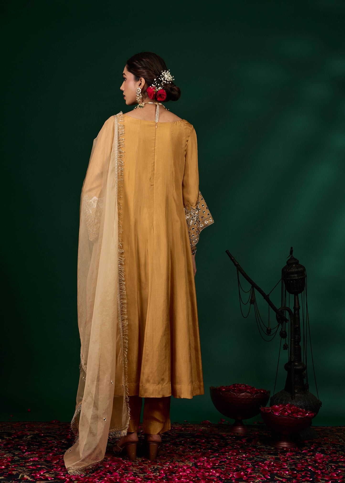 Woman in a mustard yellow traditional outfit with a green background