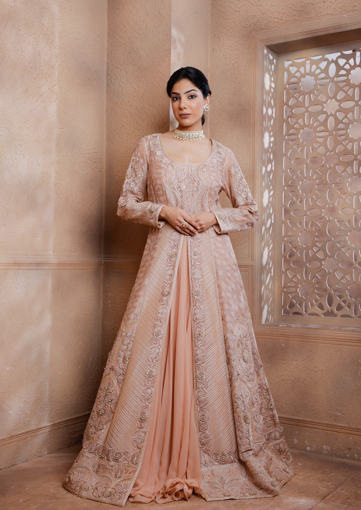 The intricately embroidered long Jacket shimmers with tonal threads, applique & hand embroidery adding a touch of opulence. Paired with a raw silk blouse and georgette lehenga.
