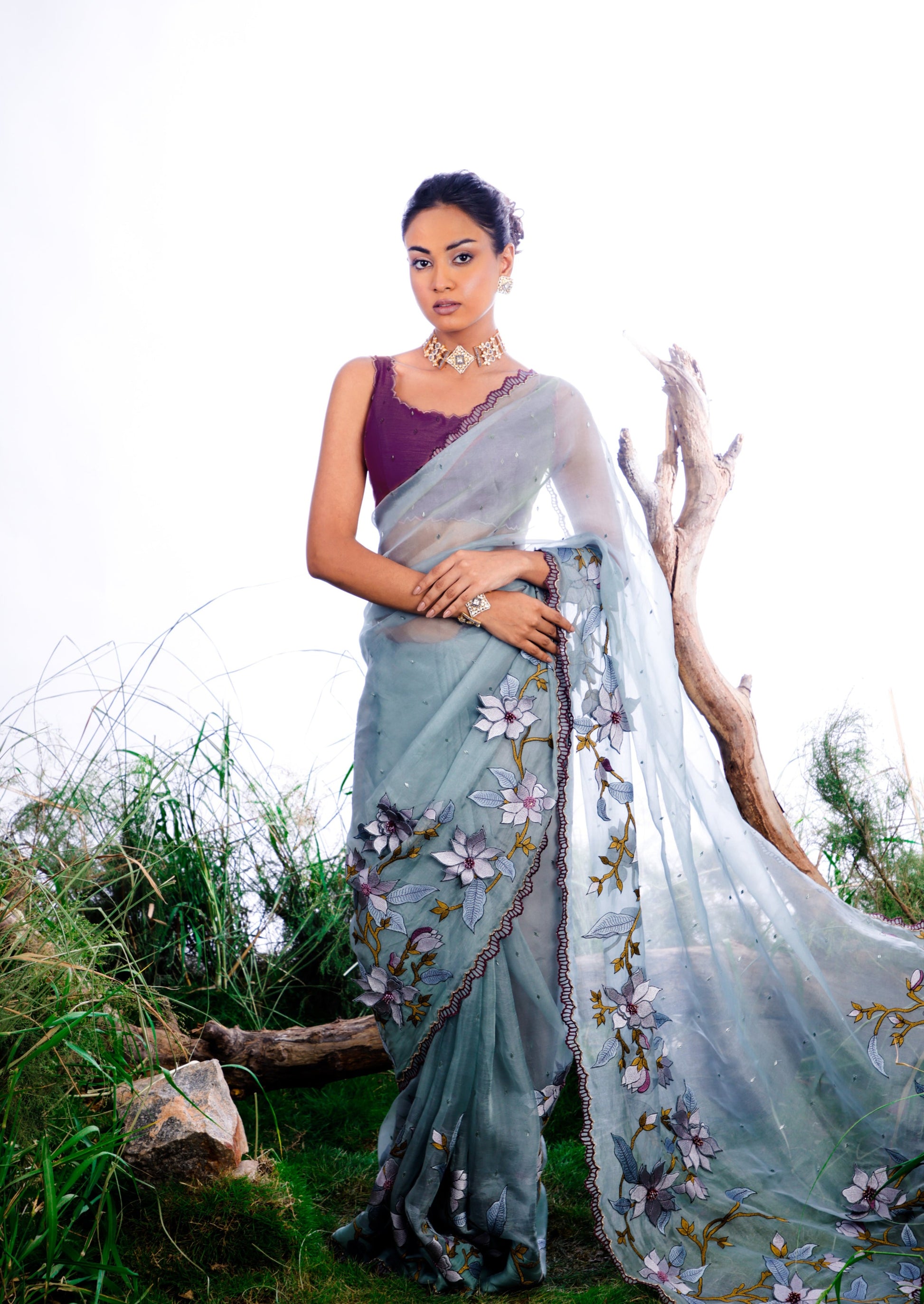 The saree features an enchanting display of 3D embroidered floral motifs that cascade like a blooming vine across the fabric.