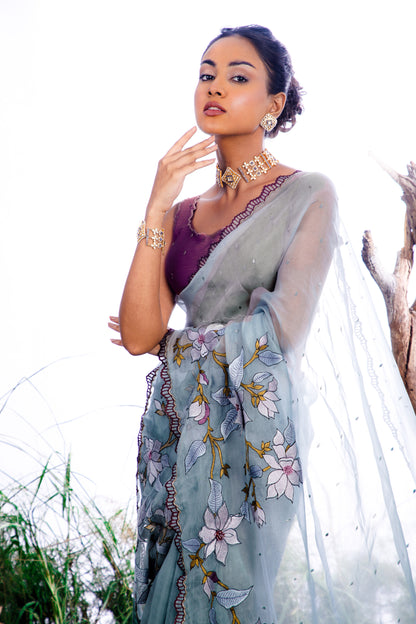 The saree features an enchanting display of 3D embroidered floral motifs that cascade like a blooming vine across the fabric.