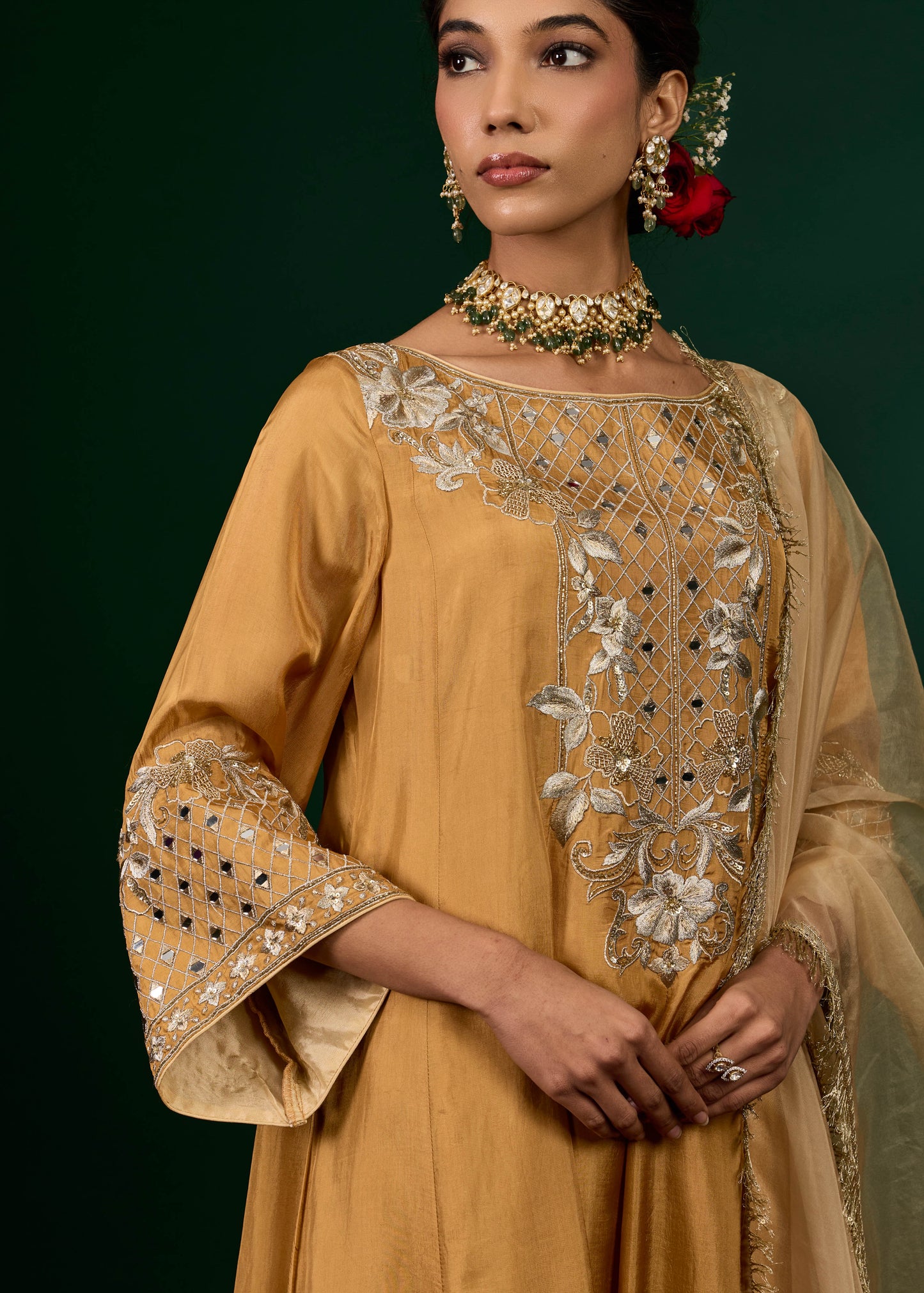 Woman wearing a mustard yellow embroidered outfit with a green background