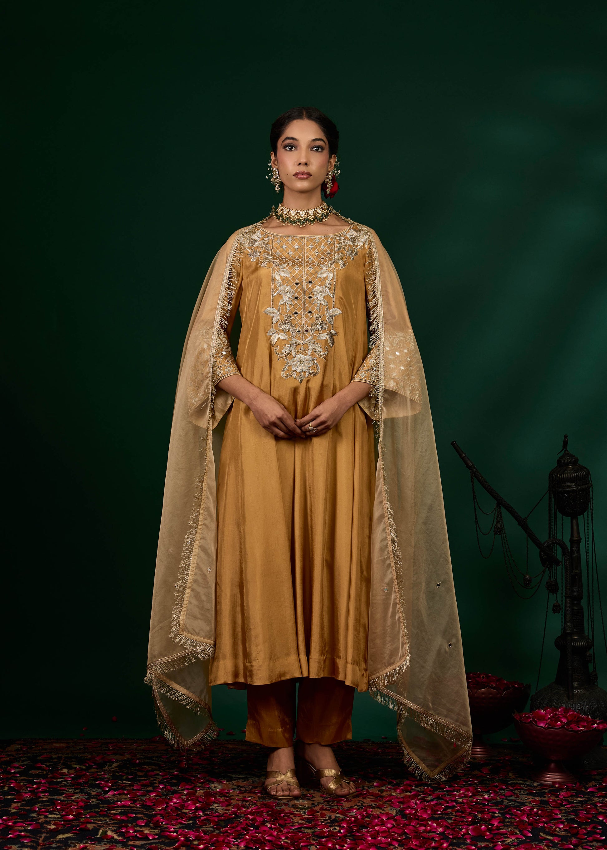 Woman in a mustard yellow traditional outfit with a green background