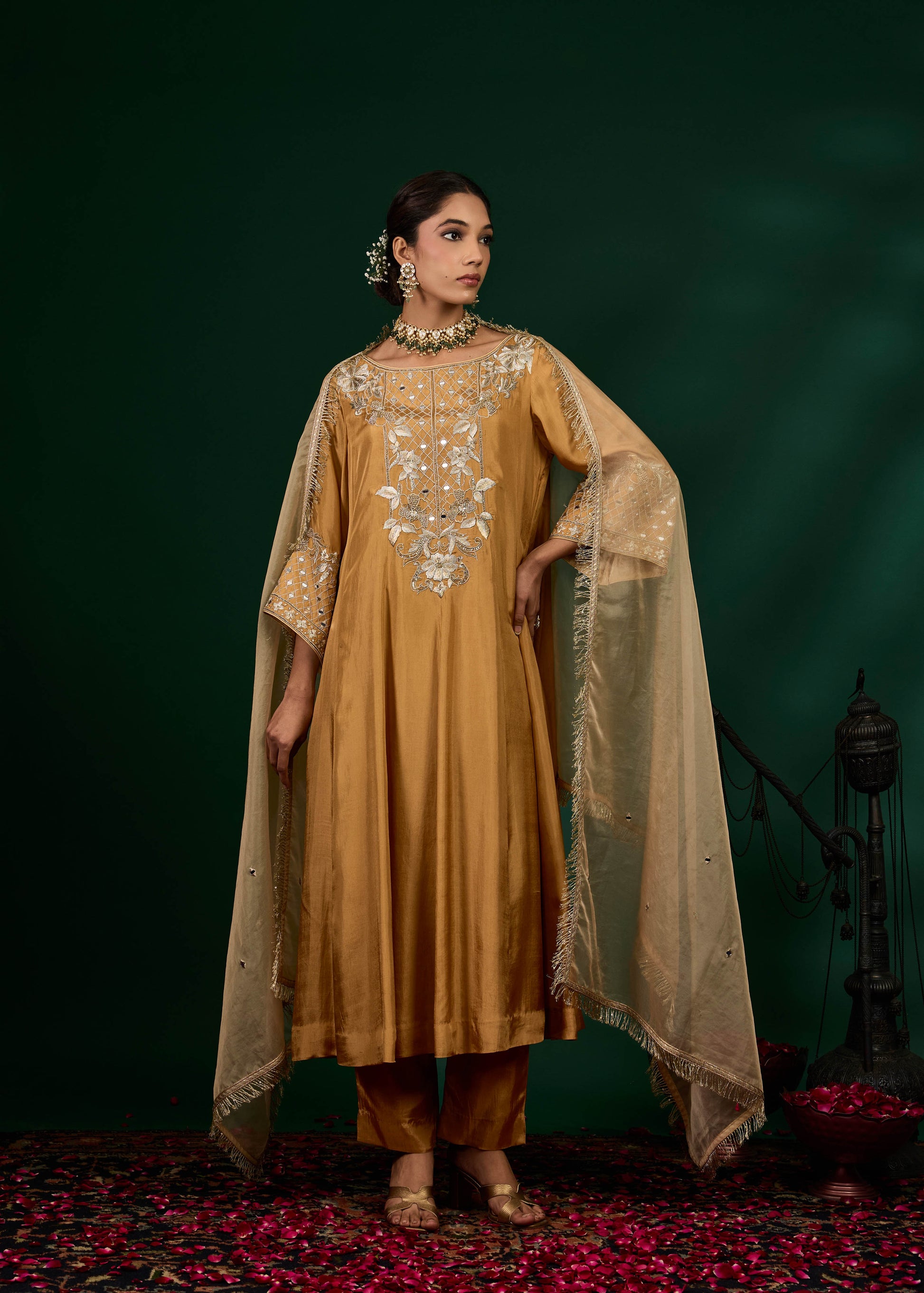 Woman in a mustard yellow traditional outfit with a green background