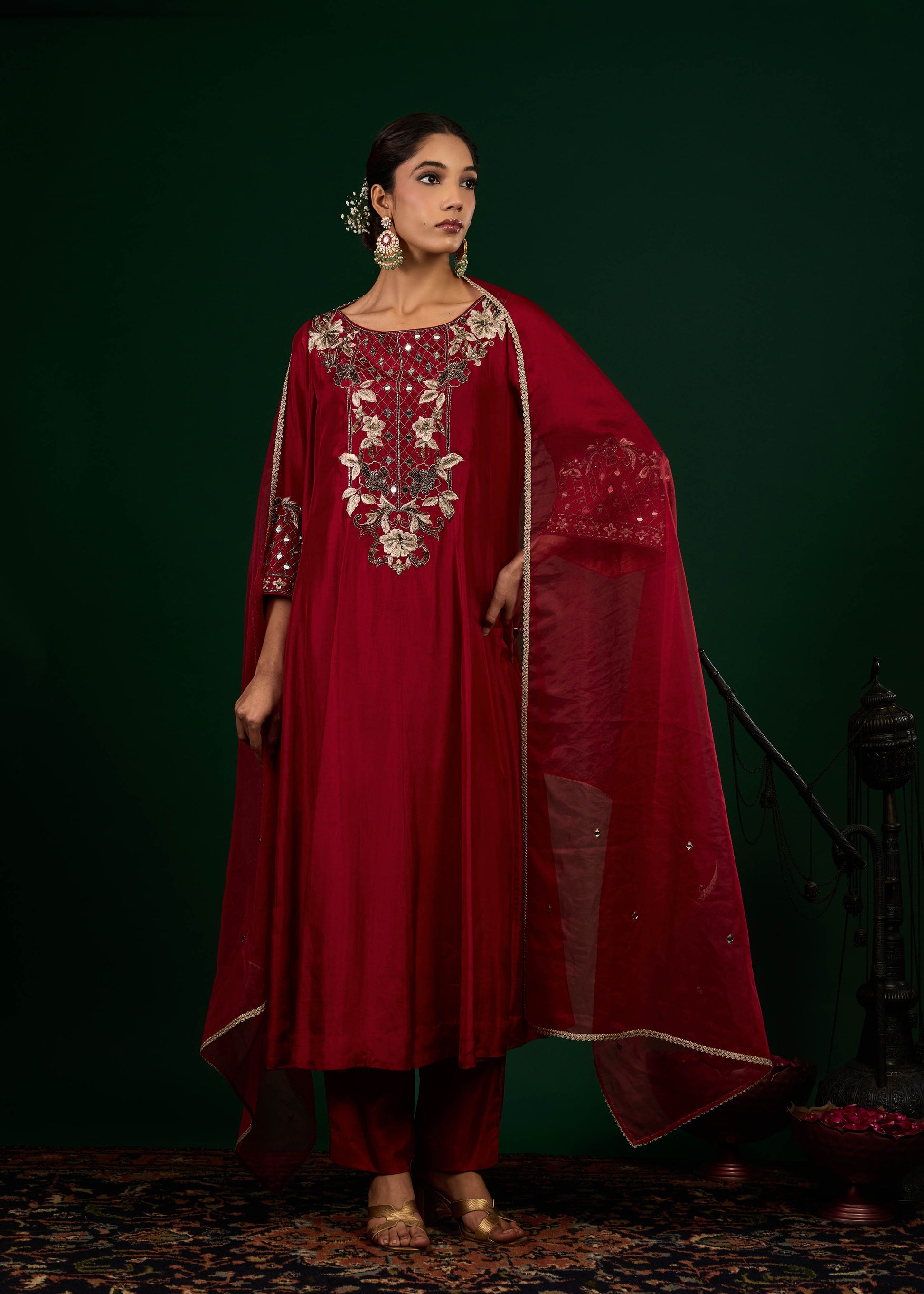 Woman wearing a red embroidered traditional outfit with a dark green background