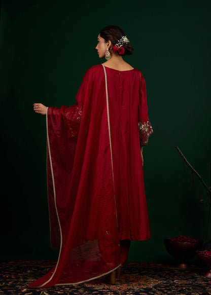 Woman in a red traditional outfit with a dark green background